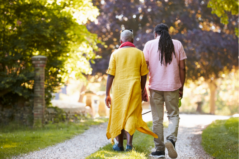 couple walking together amongst trees with their dog