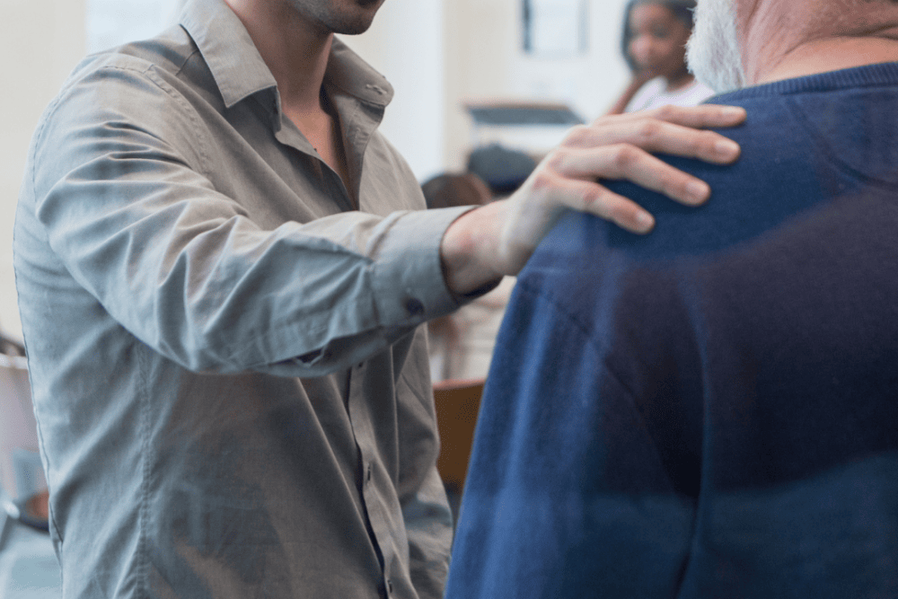 man putting hand on another man's shoulder to show him support