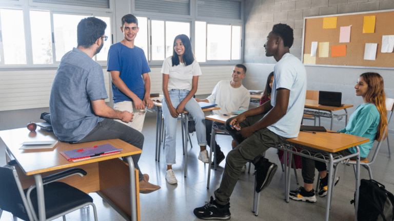 a group of young people having a conversation with their teacher at school