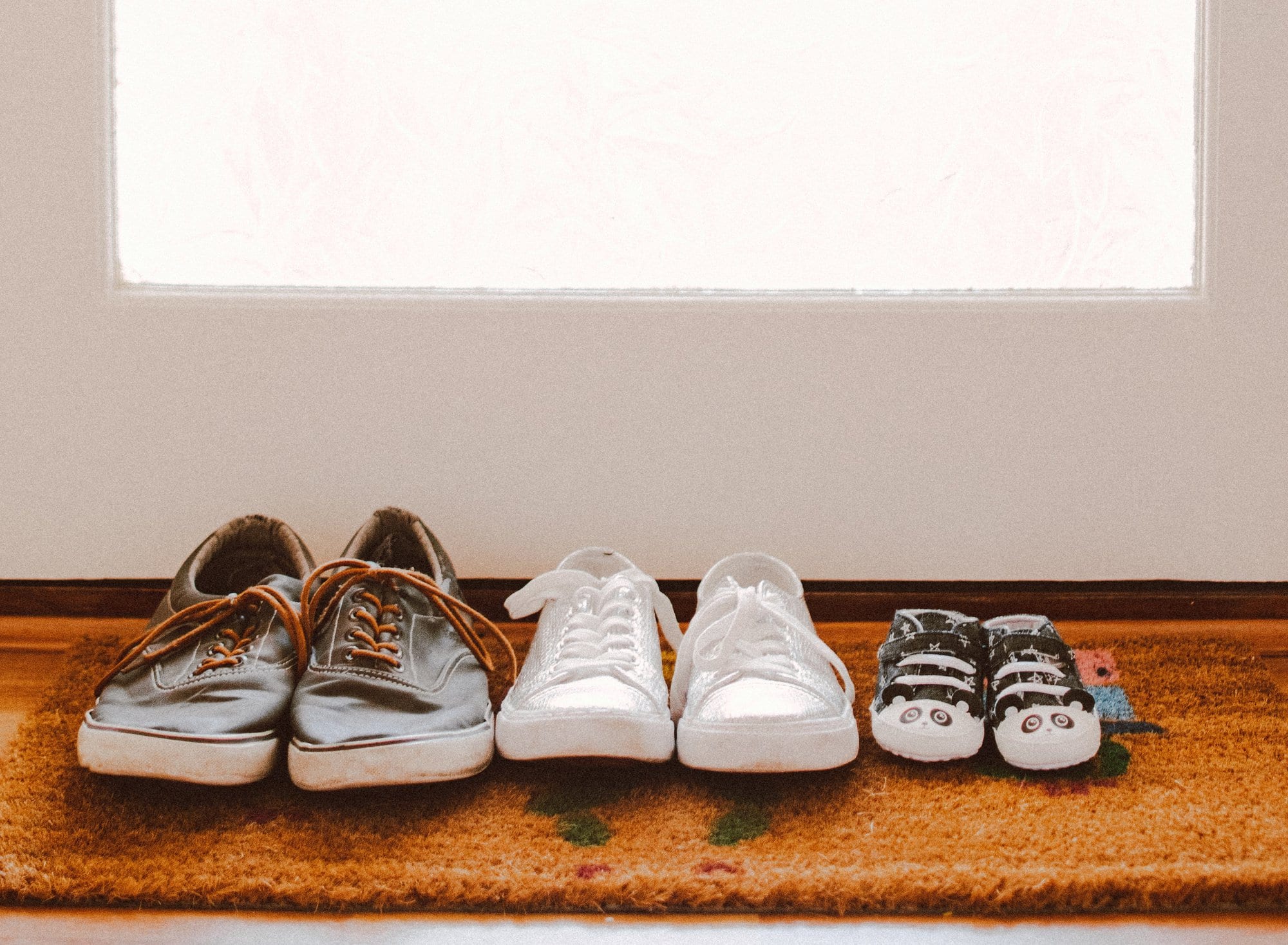 three pairs of shoes on brown rug