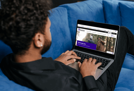 A man working on a laptop with the GamCare homepage visible